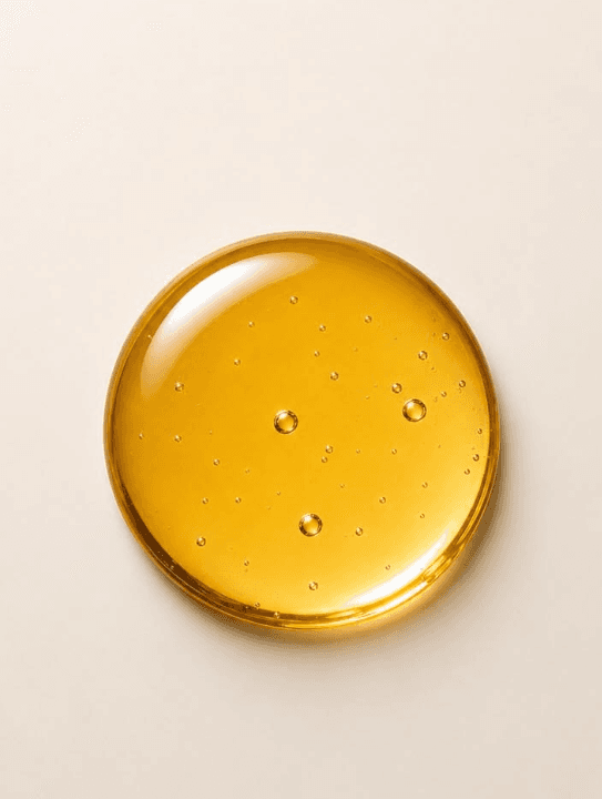 Golden oil droplet against a cream background